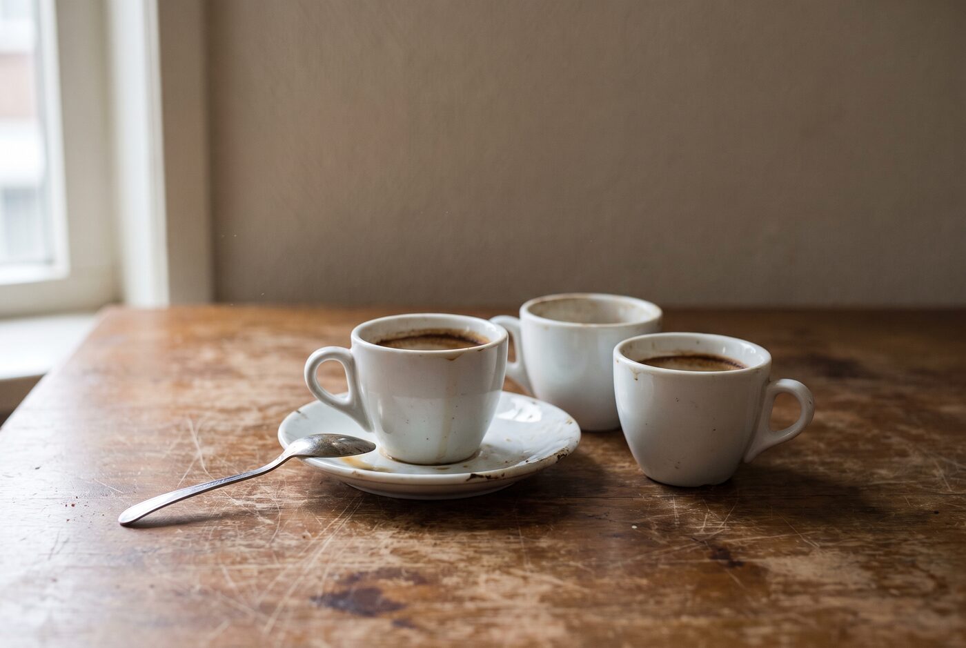 Drie gebruikte koffiekopjes op een houten bureau