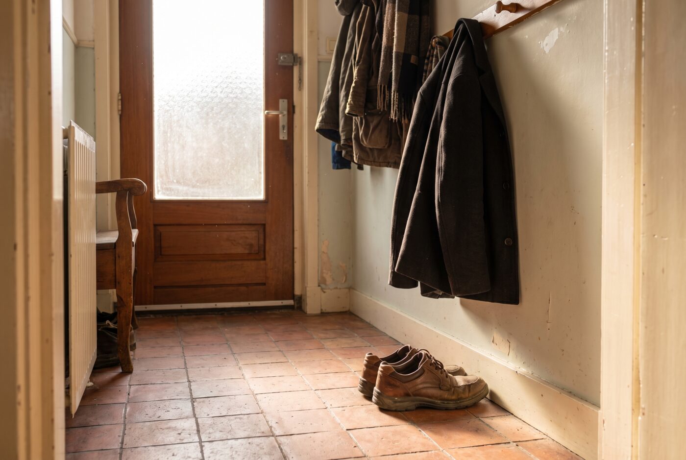 Een paar leren wandelschoenen staat onaangeroerd in een gang naast de voordeur