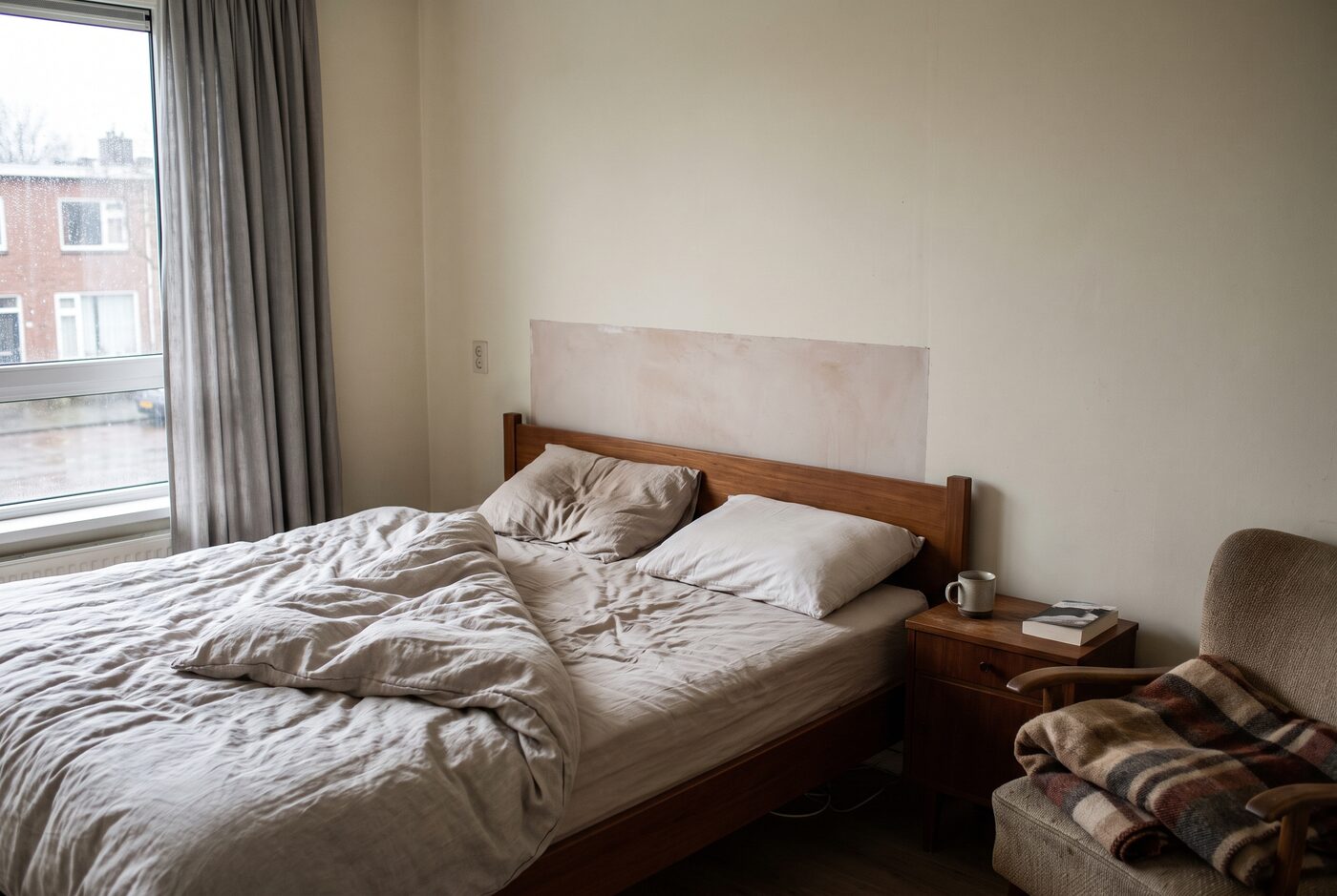 Een beslapen tweepersoonsbed in het ochtendlicht met het dekbed teruggeslagen